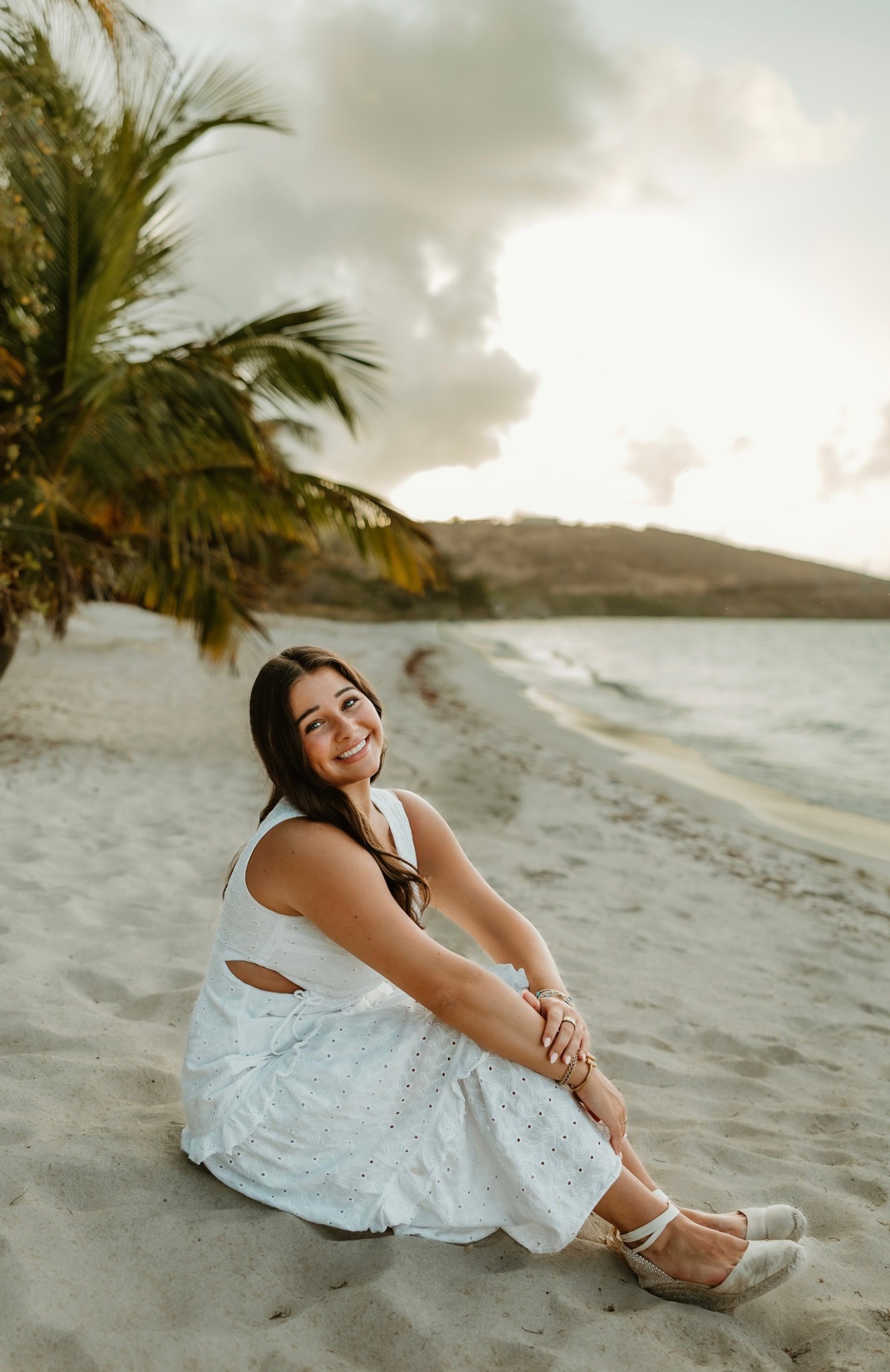 Addison Powell, founder and lead photographer of AGP Photography, sitting on a beach